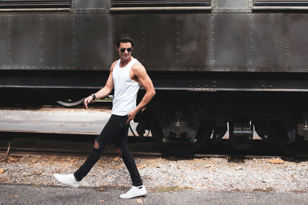 Man wearing a True Classic White Tank Top in front of railcar