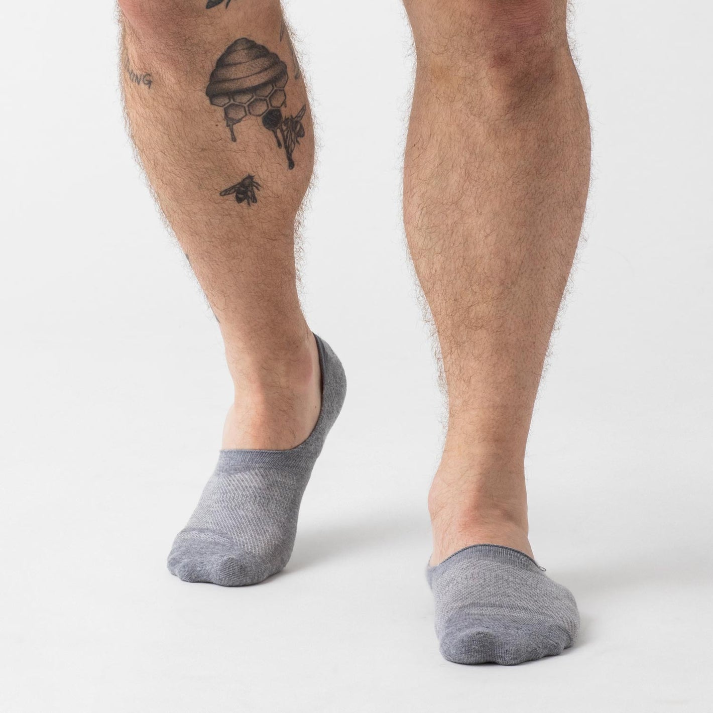 Heather Gray Never Show Socks worn on tattooed legs, showcasing no-slip fit.