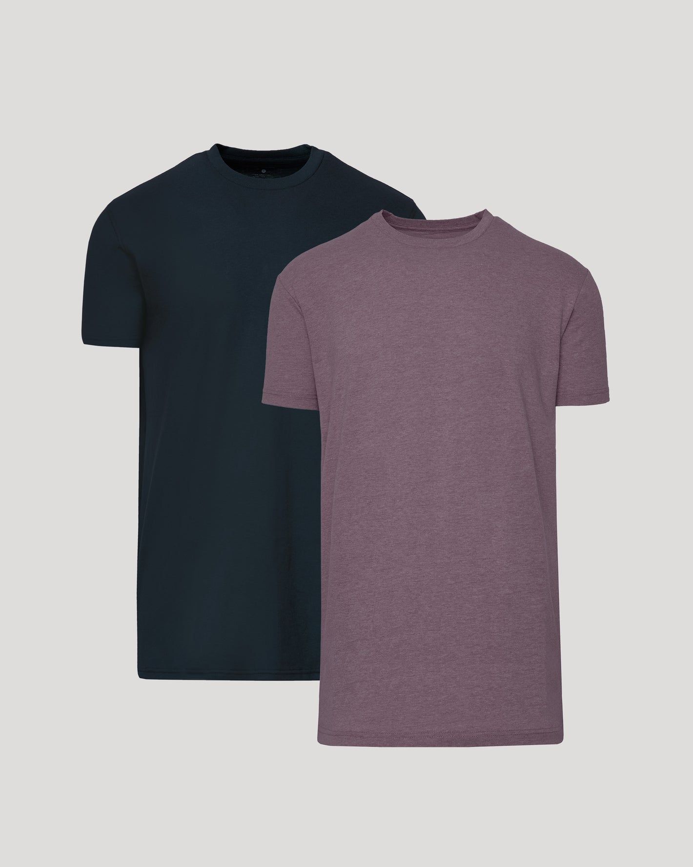Two short-sleeve crew-neck t-shirts shown on a light gray background, with one in dark navy and the other in heathered muted purple, layered slightly behind each other.