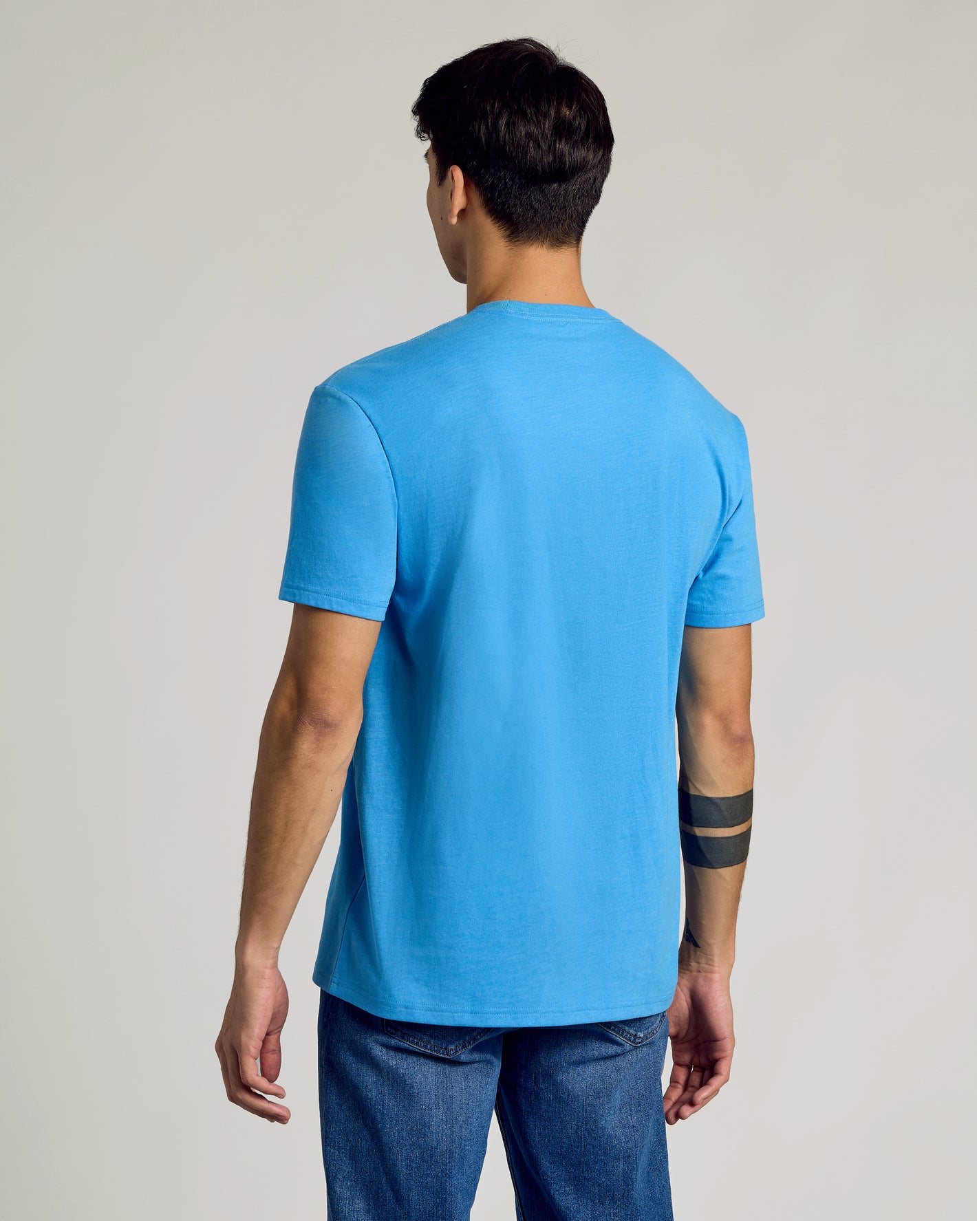 Man wearing Dark Heather Bahama Blue Classic Crew Neck, showing back and tattoos.