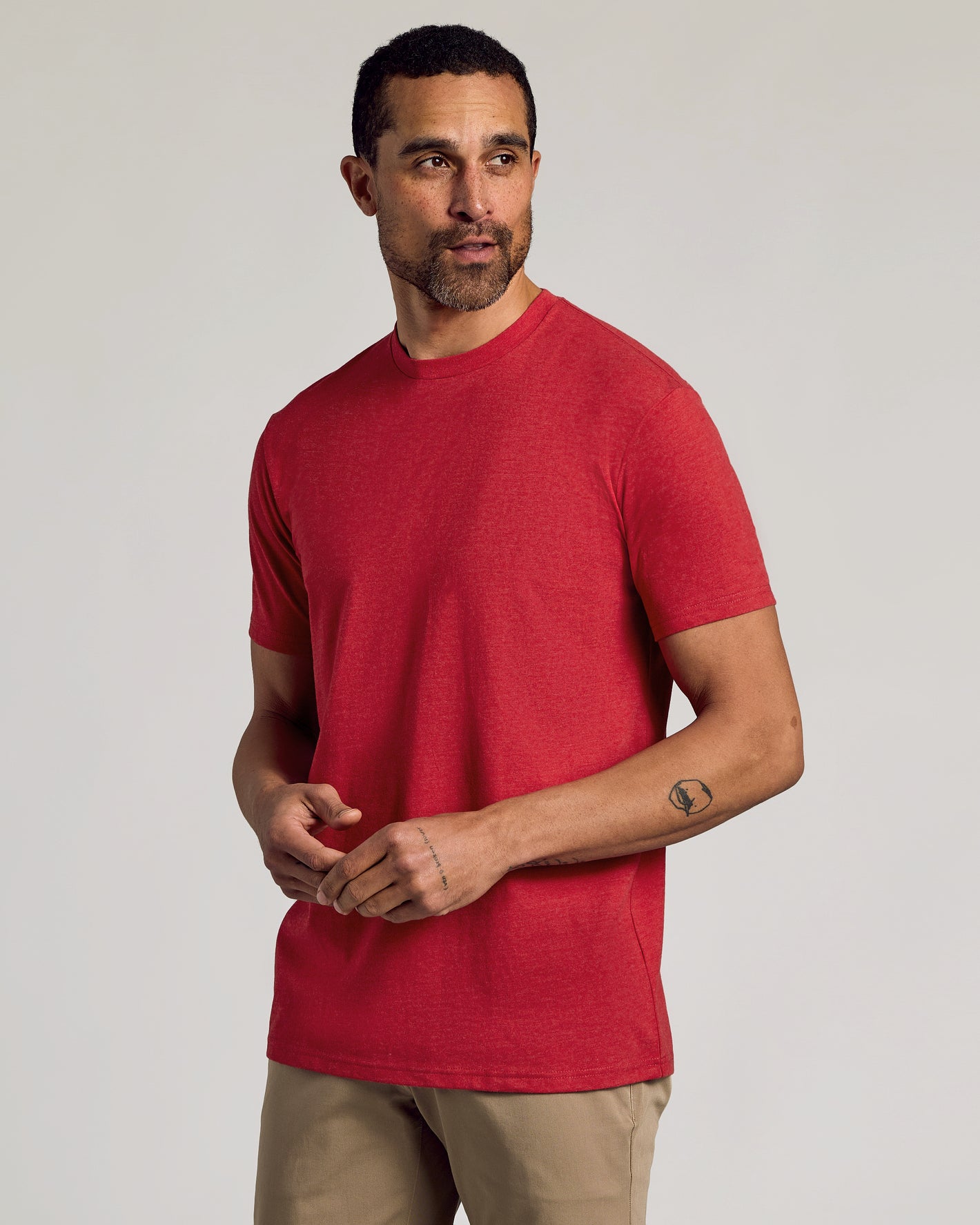 Man wearing Dark Heather Lava Short Sleeve Crew Neck Tee with beige pants.
