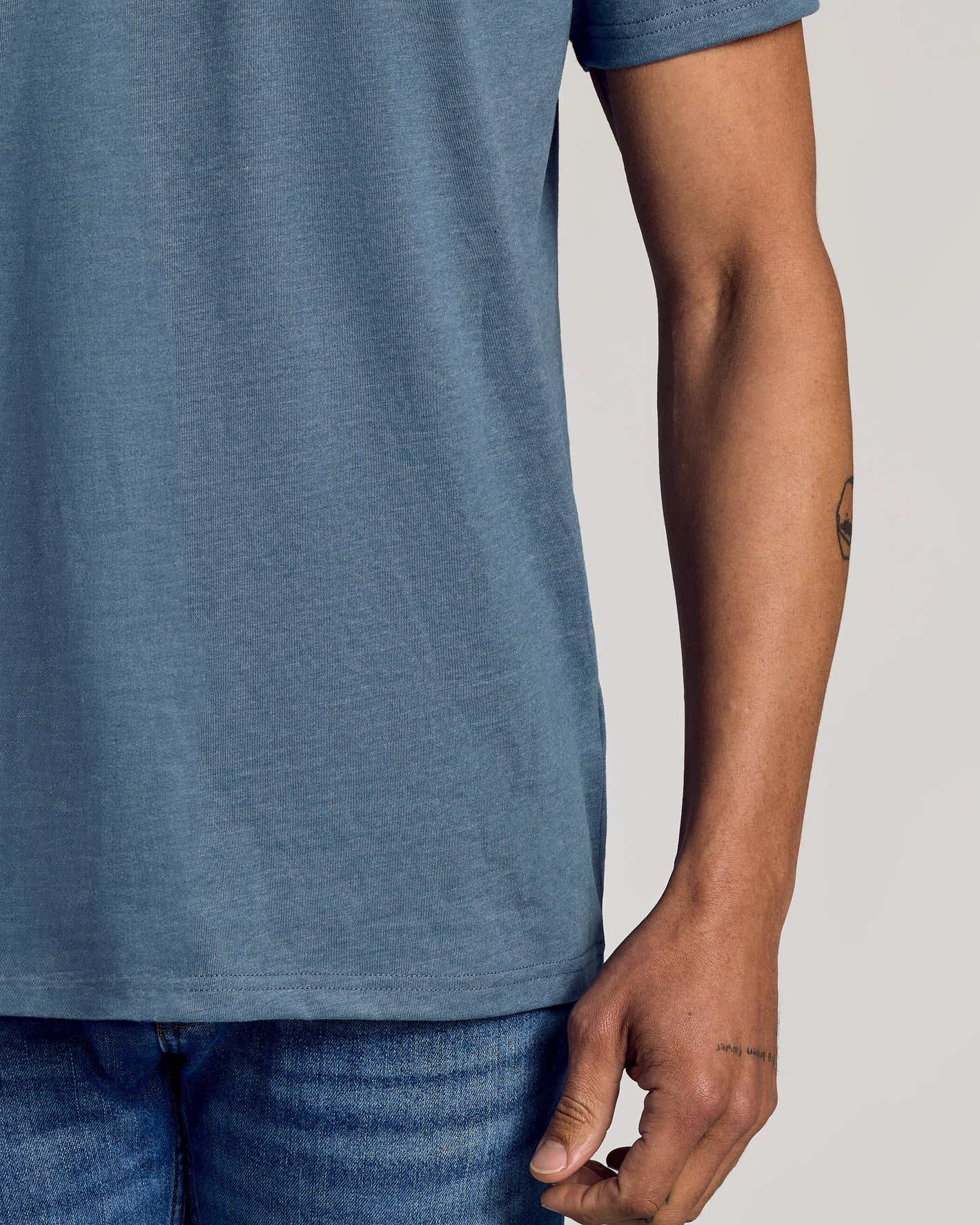 Person wearing Dark Heather Tempest Classic Crew Neck with medium-wash jeans.