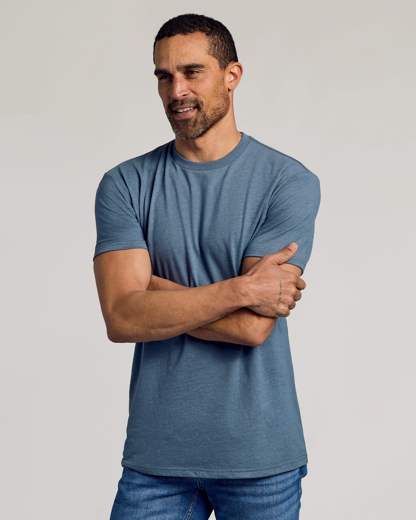 Man wearing Dark Heather Tempest Classic Crew Neck T-shirt and jeans.