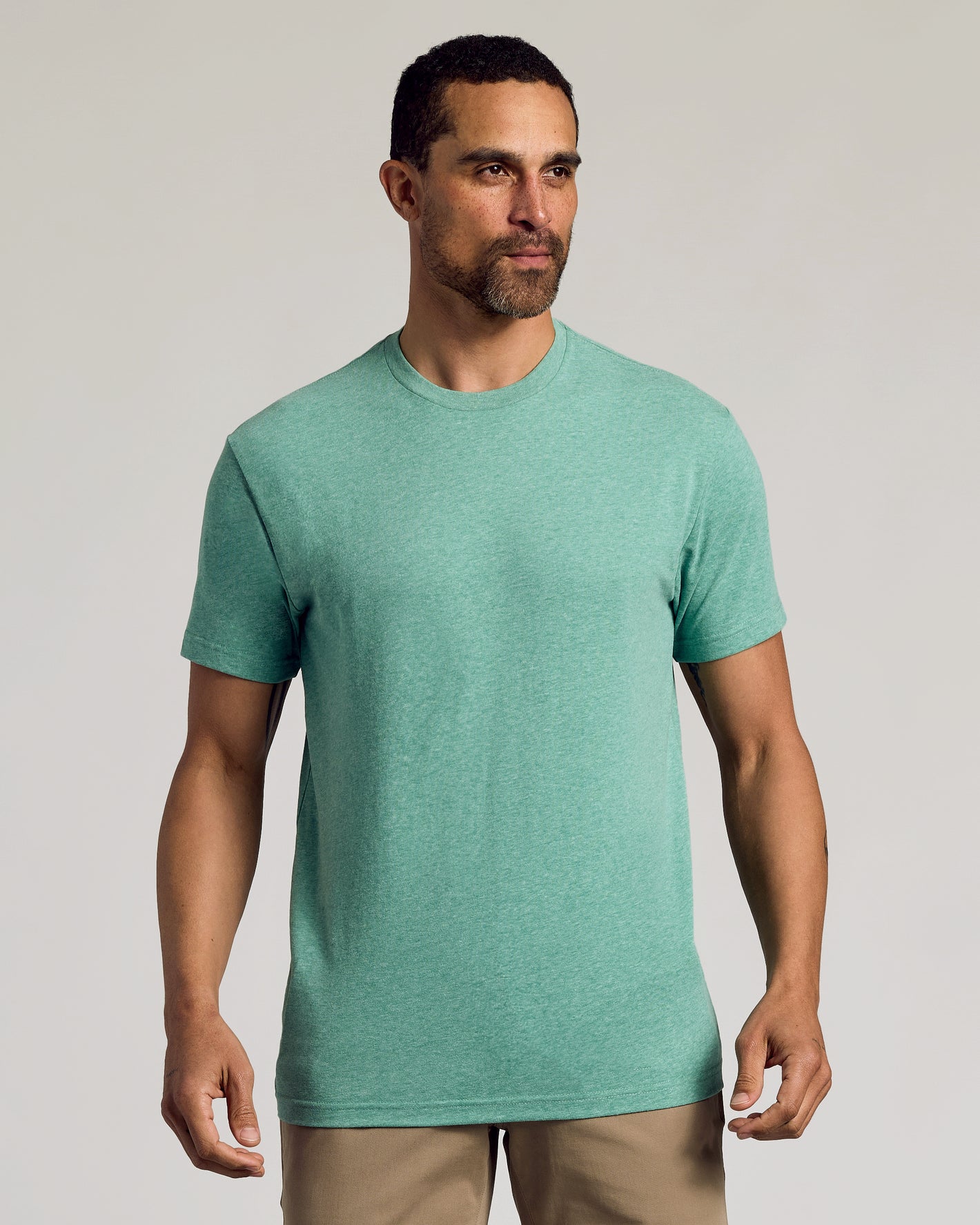 Man wearing Light Heather Greenery Classic Crew Neck and tan pants.