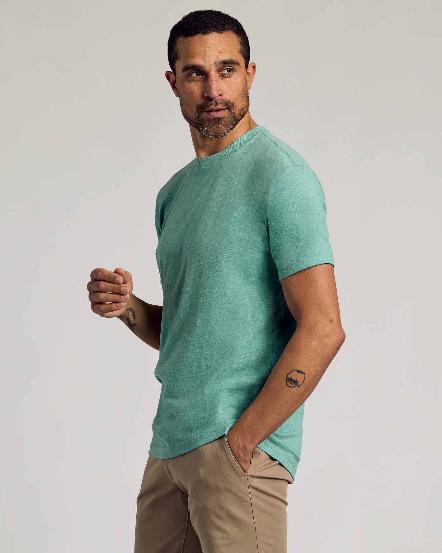 Man wearing Light Heather Greenery Classic Crew Neck and khaki trousers.