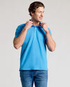 Man wears Dark Heather Bahama Blue Short Sleeve Polo, adjusting collar.