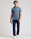Man wearing Dark Heather Tempest Short Sleeve Polo, navy trousers, white sneakers.