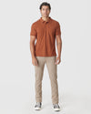 Man wearing Heather Gingersnap Mane Classic Polo with tan pants and black sneakers.