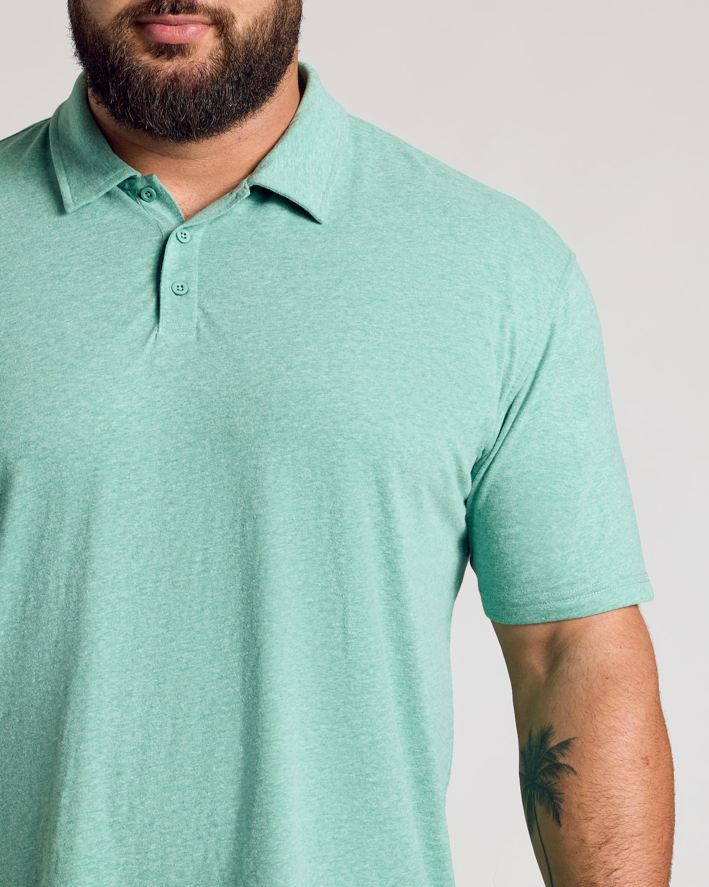Light Heather Greenery Classic Polo worn by man with palm tree tattoo.