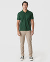 Man wears Moss Green Polo, beige pants, black sneakers.