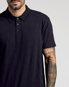 True ClassicMan wearing Black Classic Polo with tattooed forearm visible.