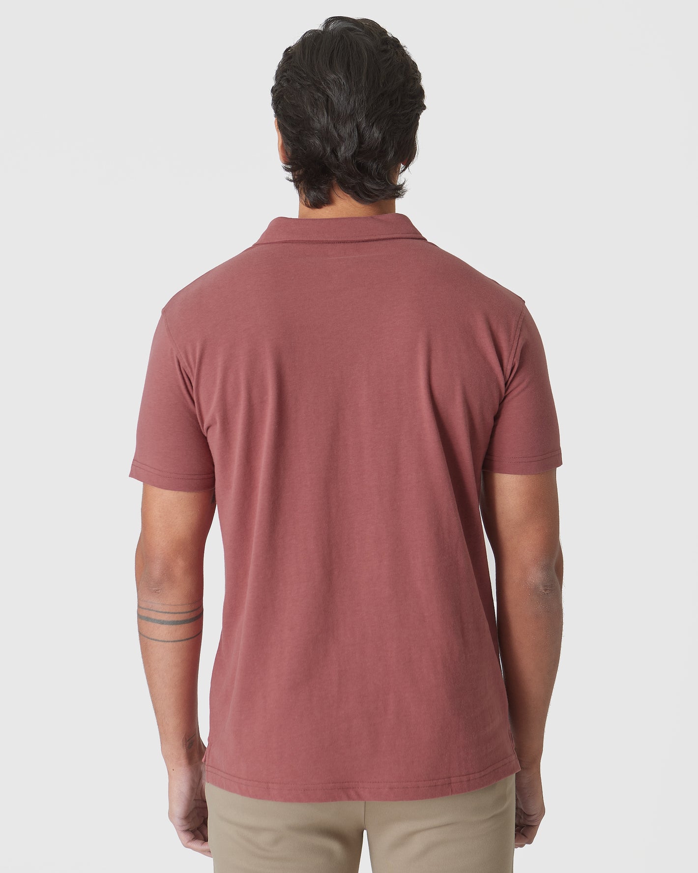 Back view of Rustic Apple Polo on model with tattooed forearm.