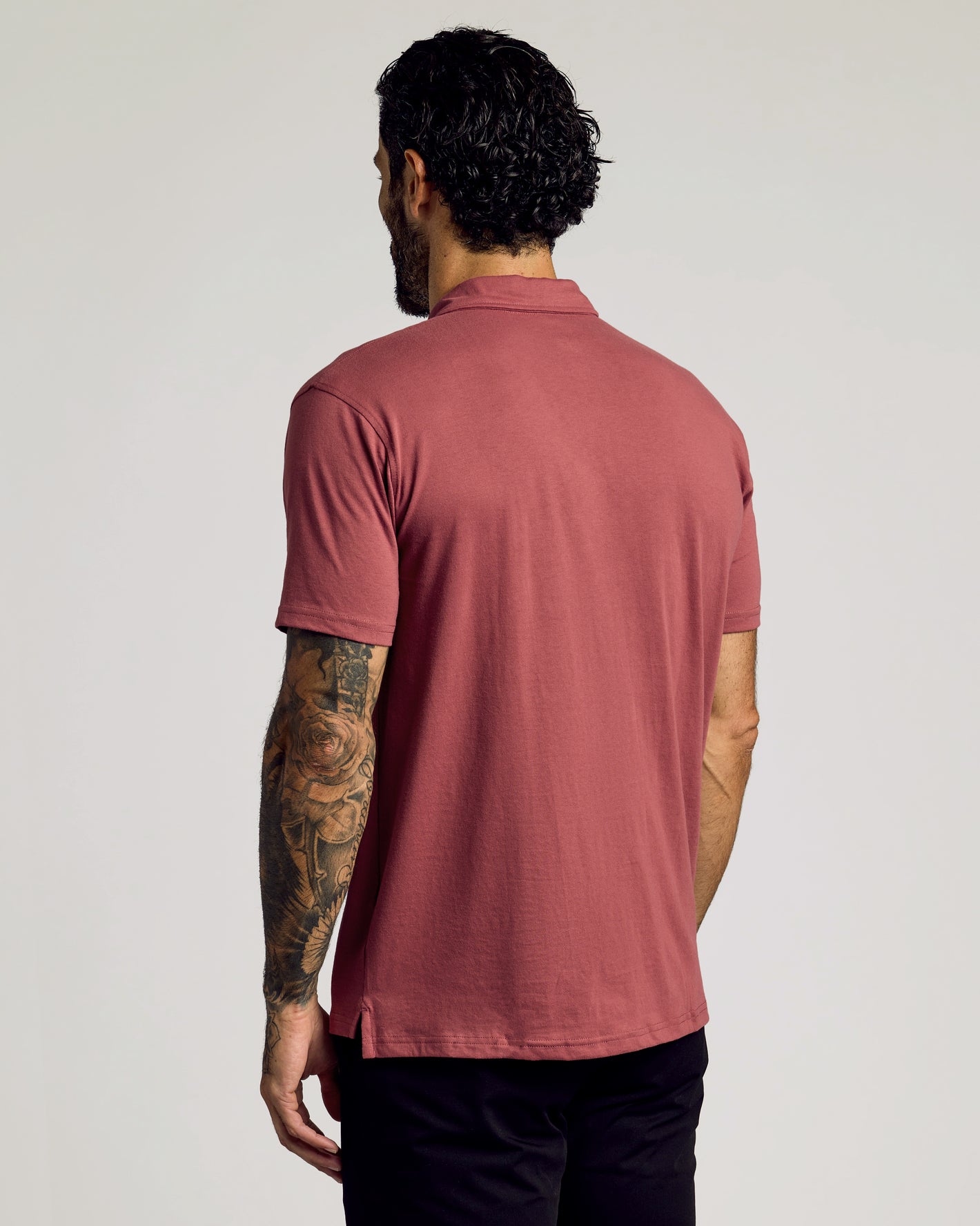 Rear view of Rustic Apple Classic Polo worn by tattooed man.