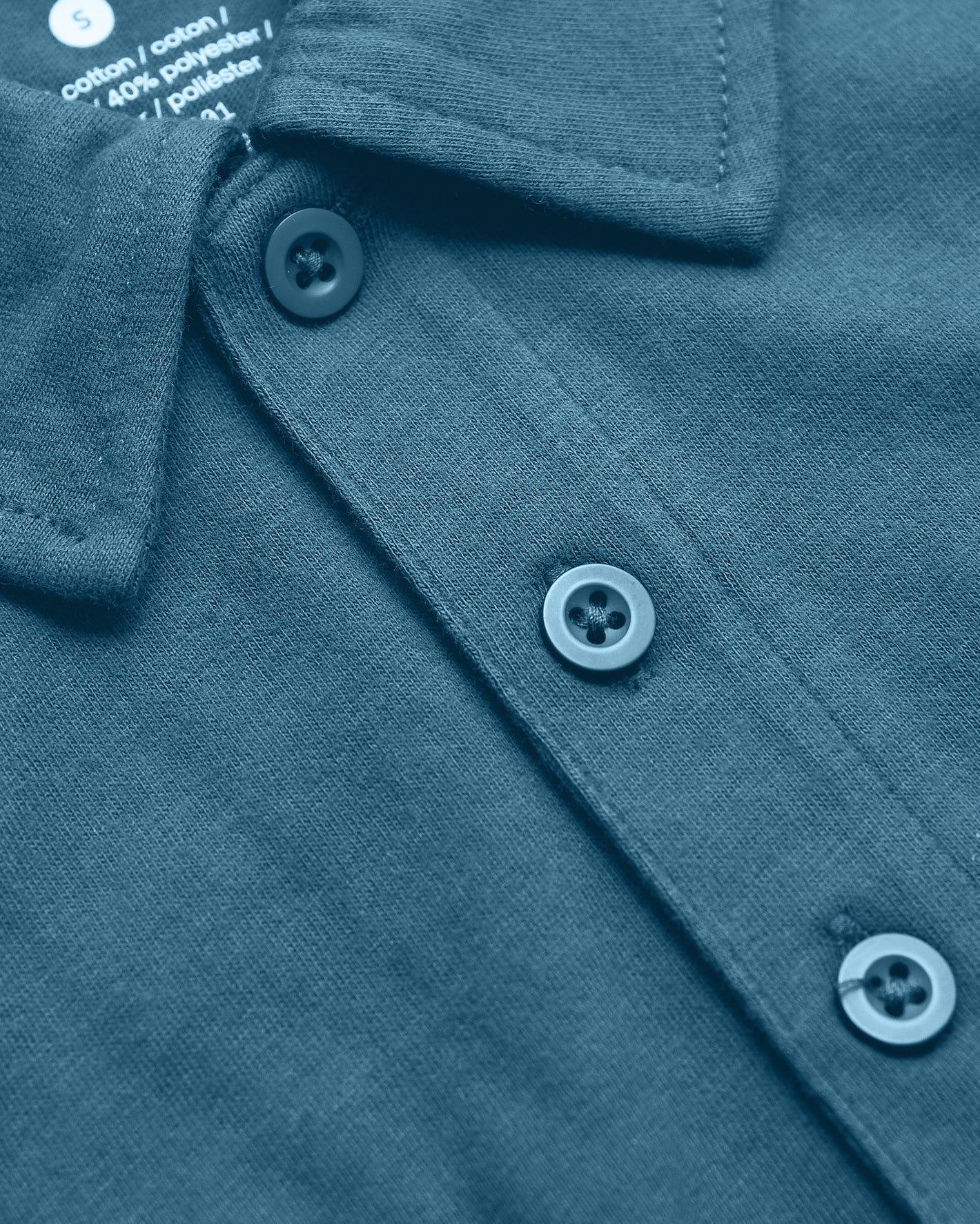 Sapphire Classic Polo close-up: folded collar, three-button placket, care label.