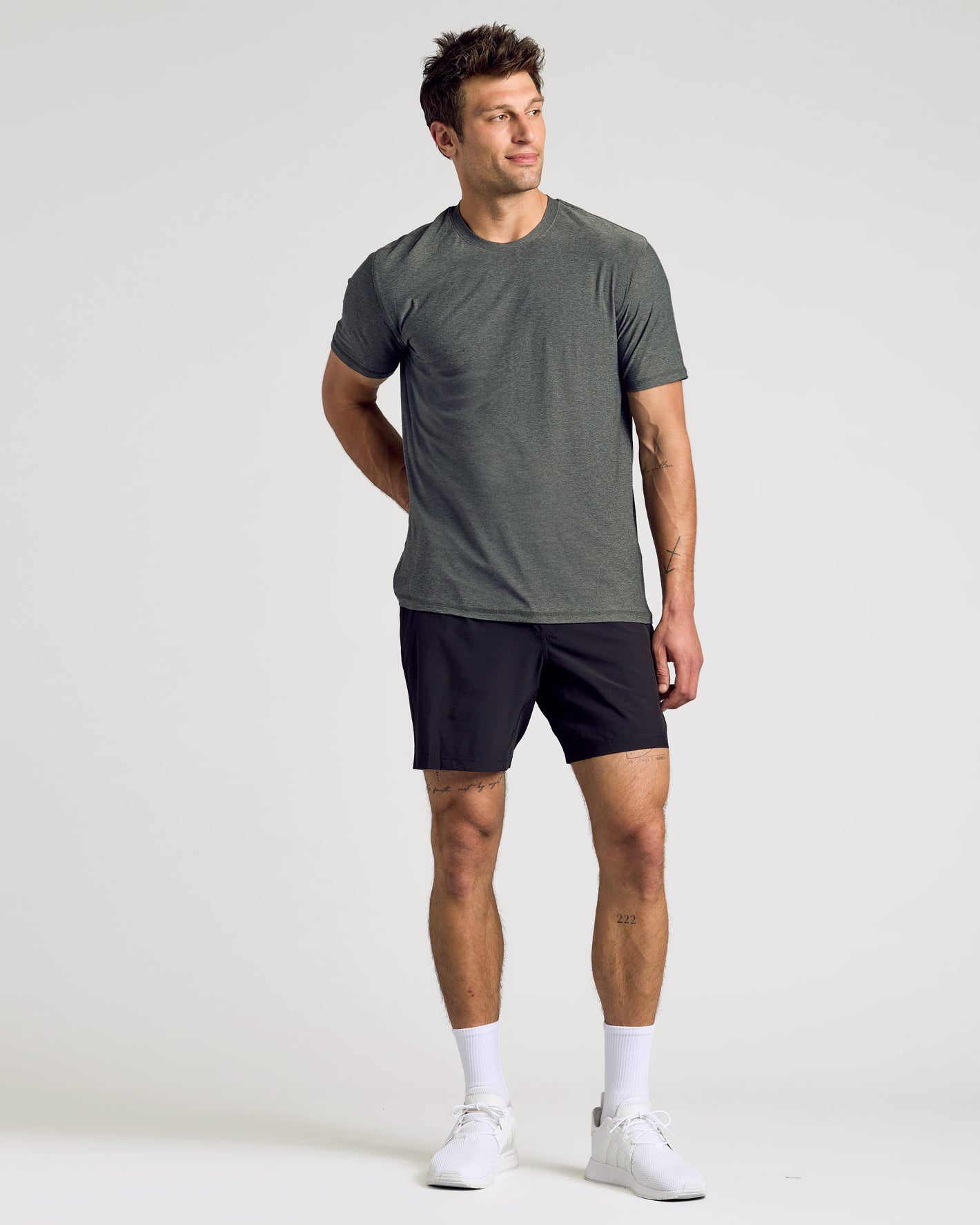 Man wearing a gray t-shirt and black shorts on a white background