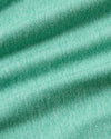 A close-up of mint green knit fabric with soft diagonal folds and visible woven texture.