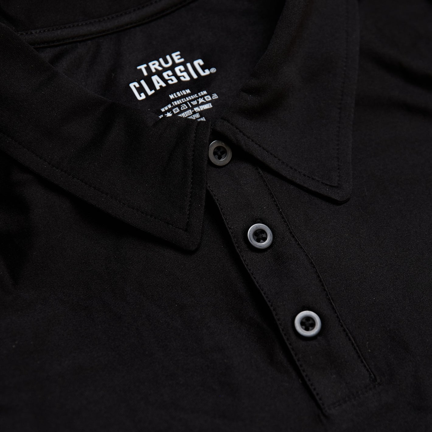 Black Active Polo 3-Pack, close-up of collar, buttons, and label.