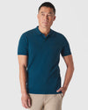 Man wearing Centurion Short Sleeve Sweater Polo in teal with beige trousers.