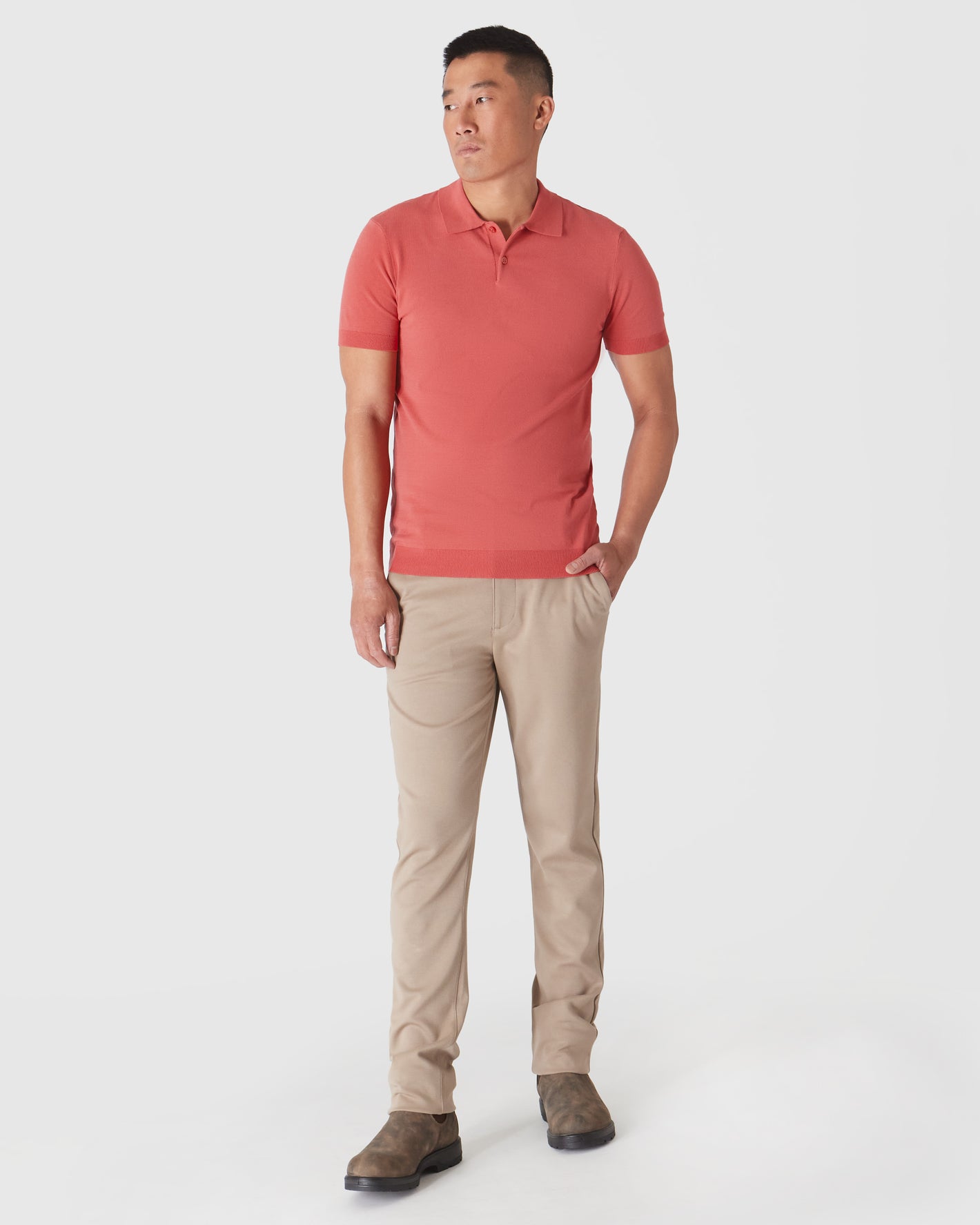 Man models Garnet Short Sleeve Sweater Polo with beige chinos and boots.