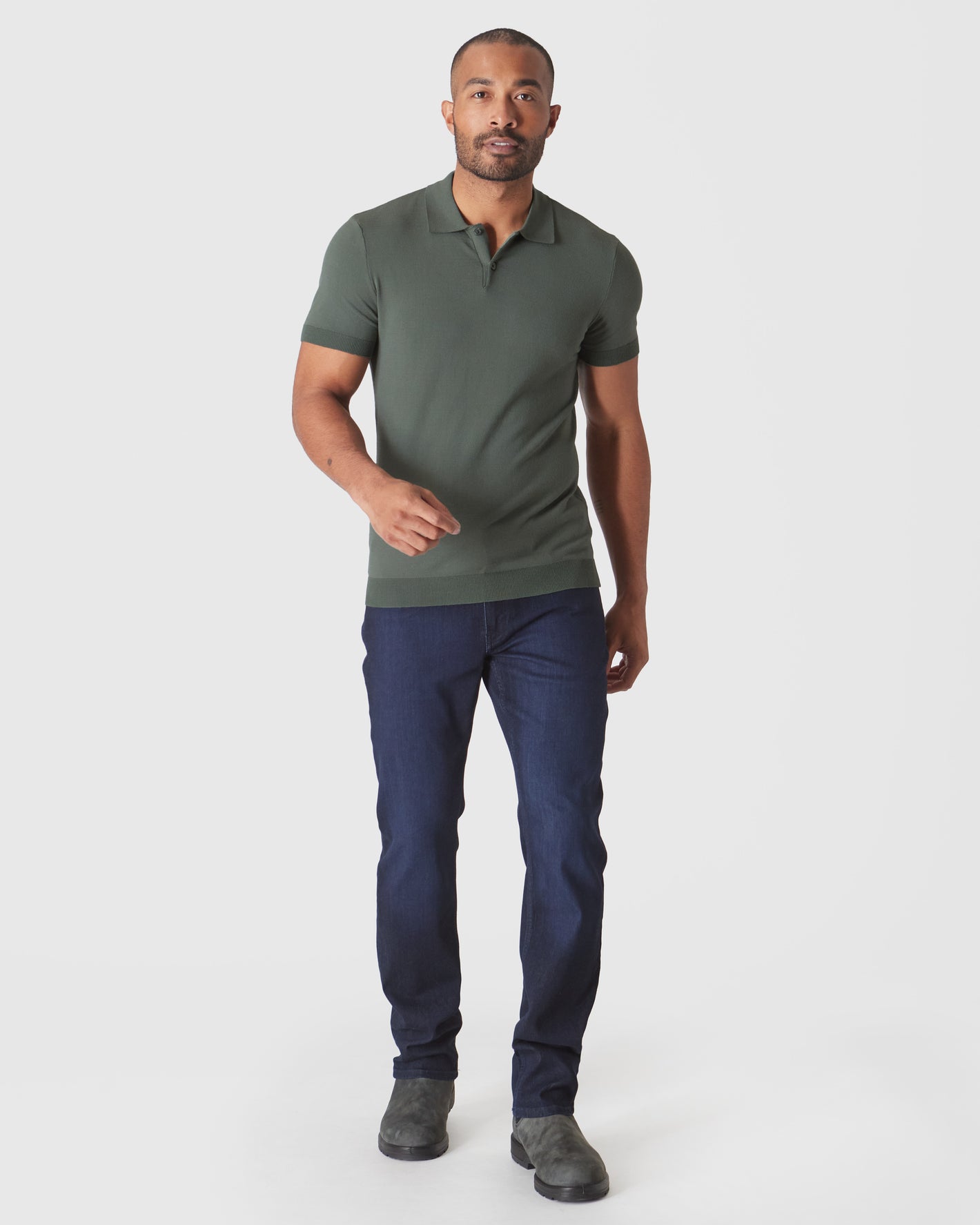 Model wearing Moss Short Sleeve Sweater Polo, dark jeans, gray Chelsea boots.