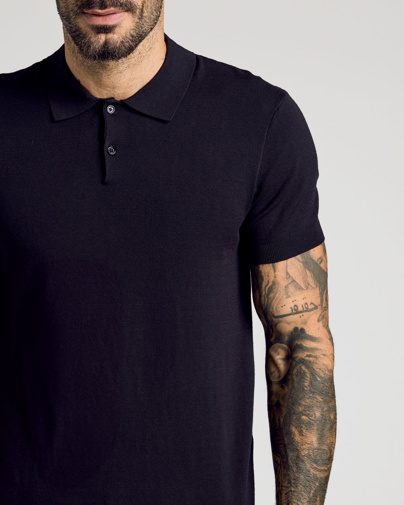 Black Short Sleeve Sweater Polo worn by tattooed man, showcasing slim fit.