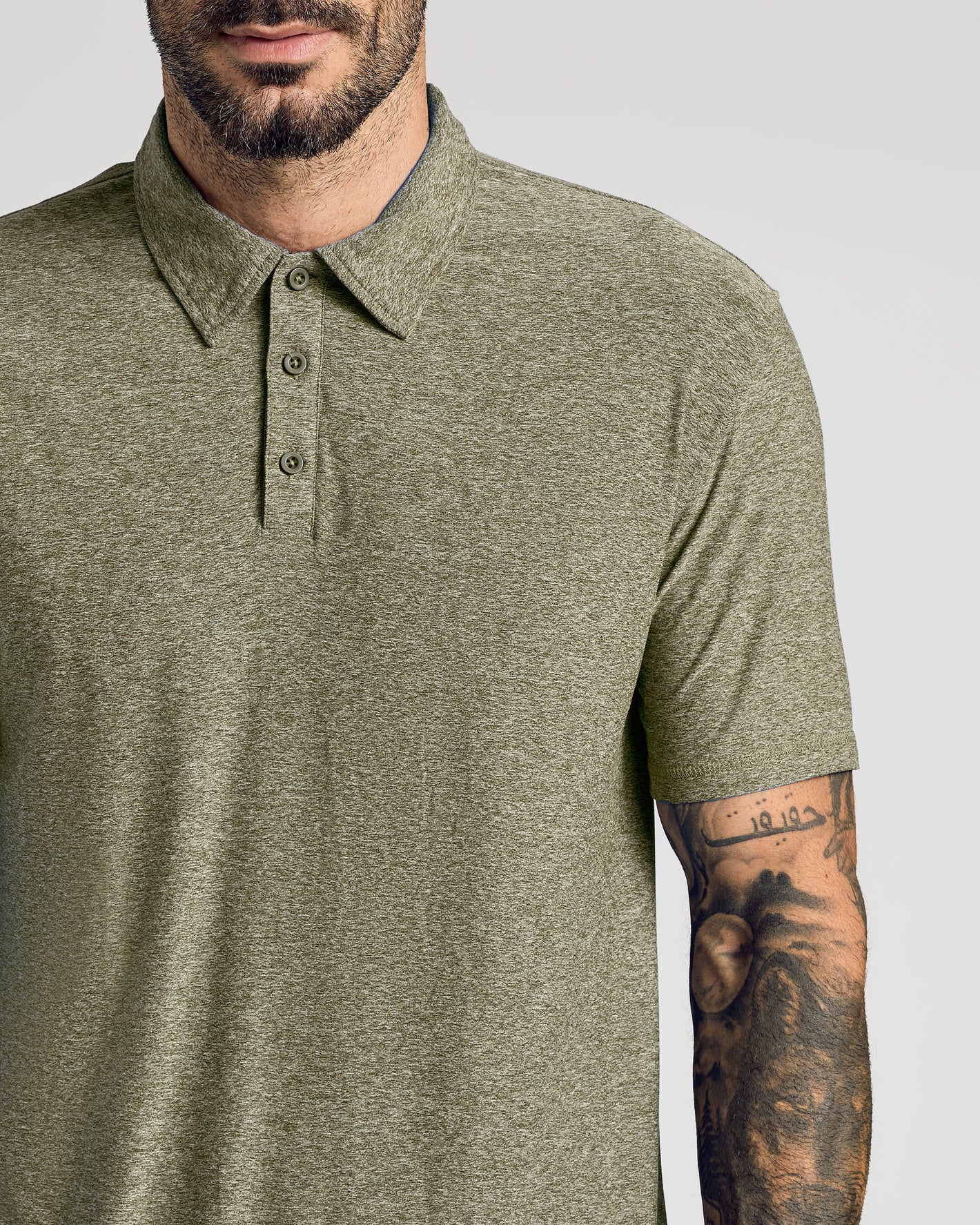 Man wearing olive-green Active Polo 10-Pack, showcasing tattooed forearm.