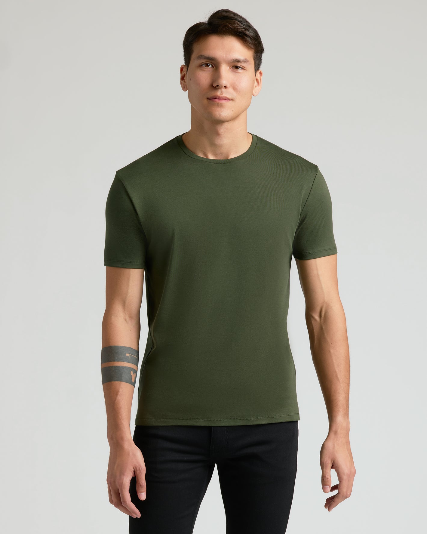 Young man in Premium Pima Crew olive tee and black pants.