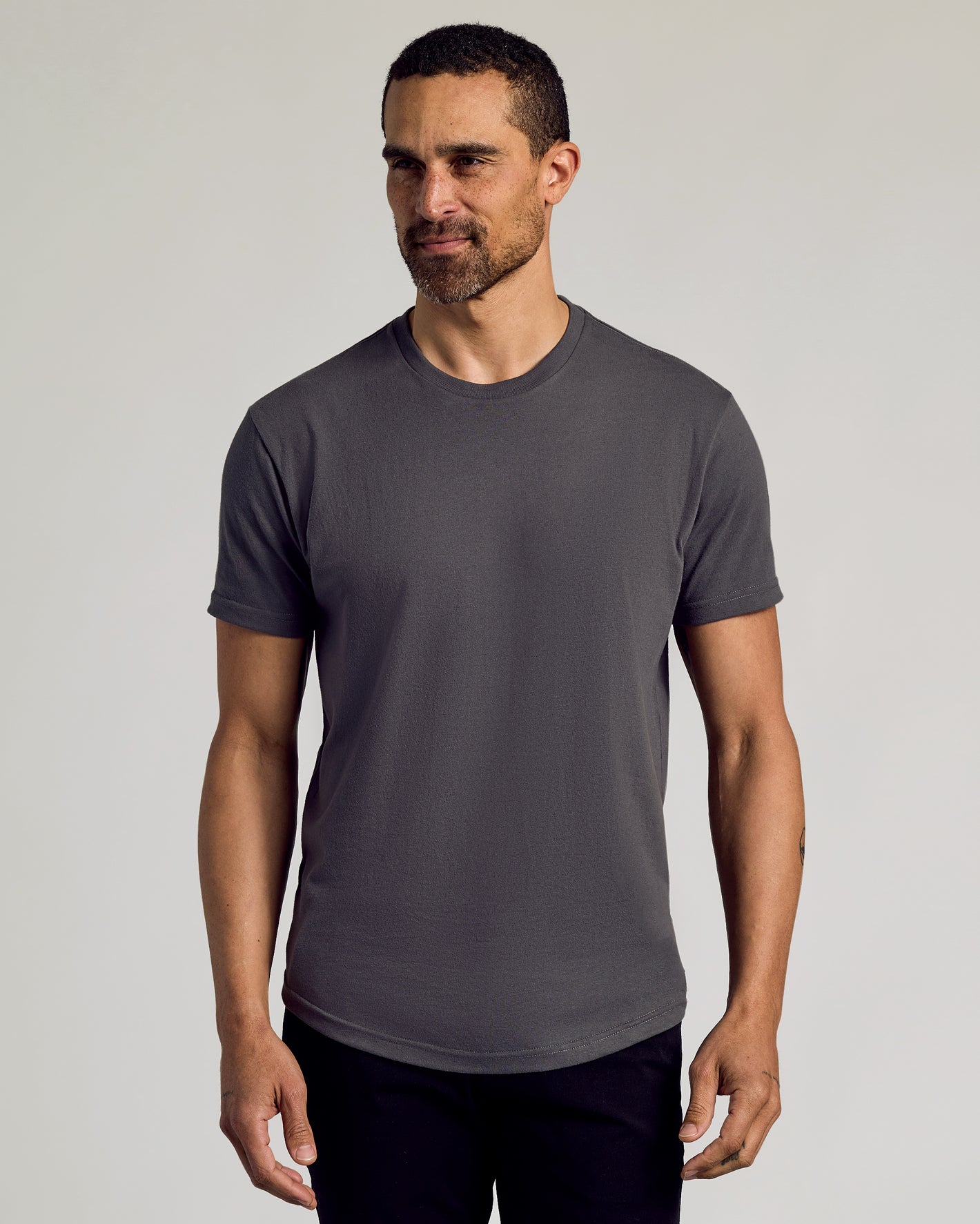 Man wearing a plain gray t-shirt against a light gray background