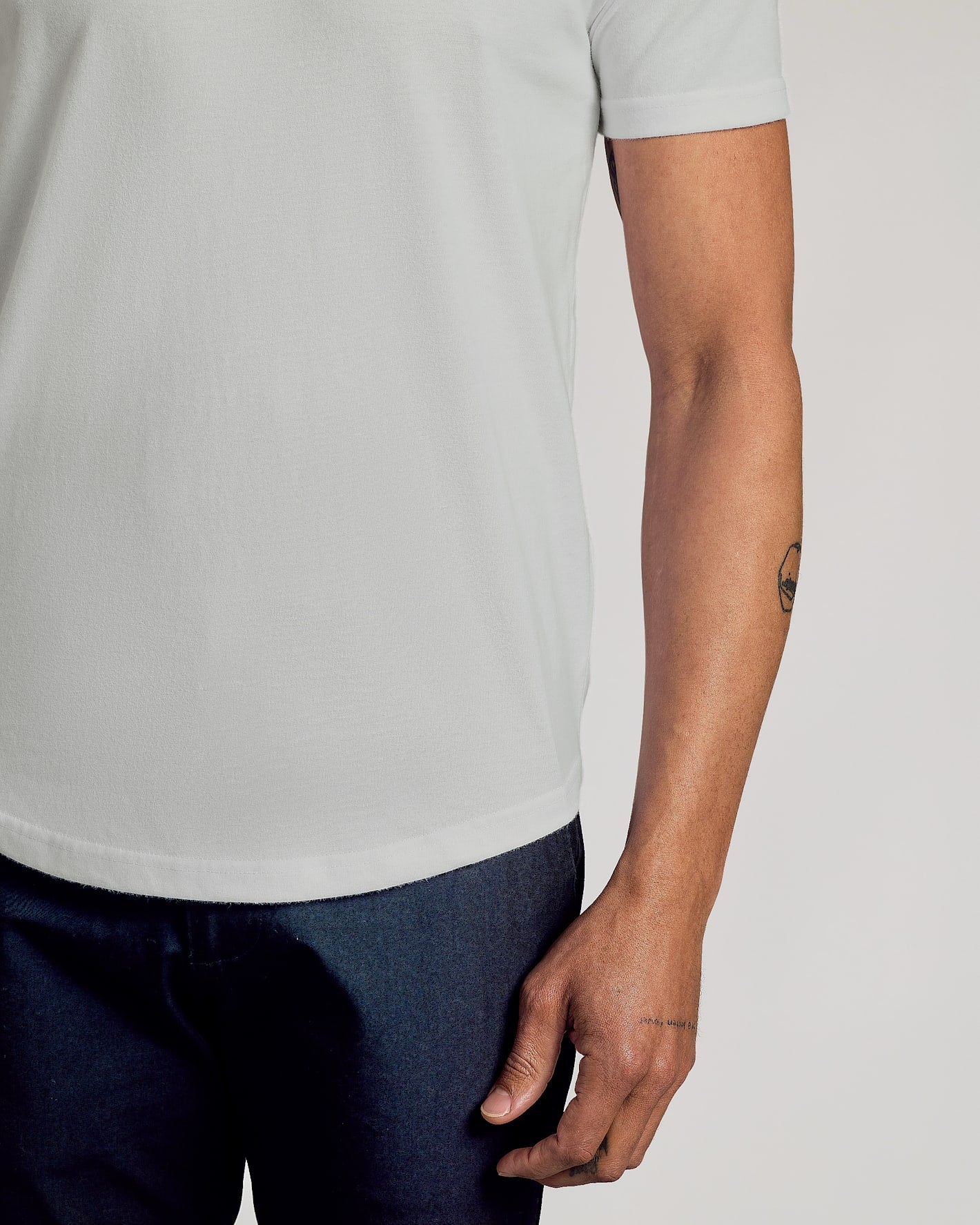 Vapor Curved Hem Classic Crew Neck on model's arm, showcasing tattoos.
