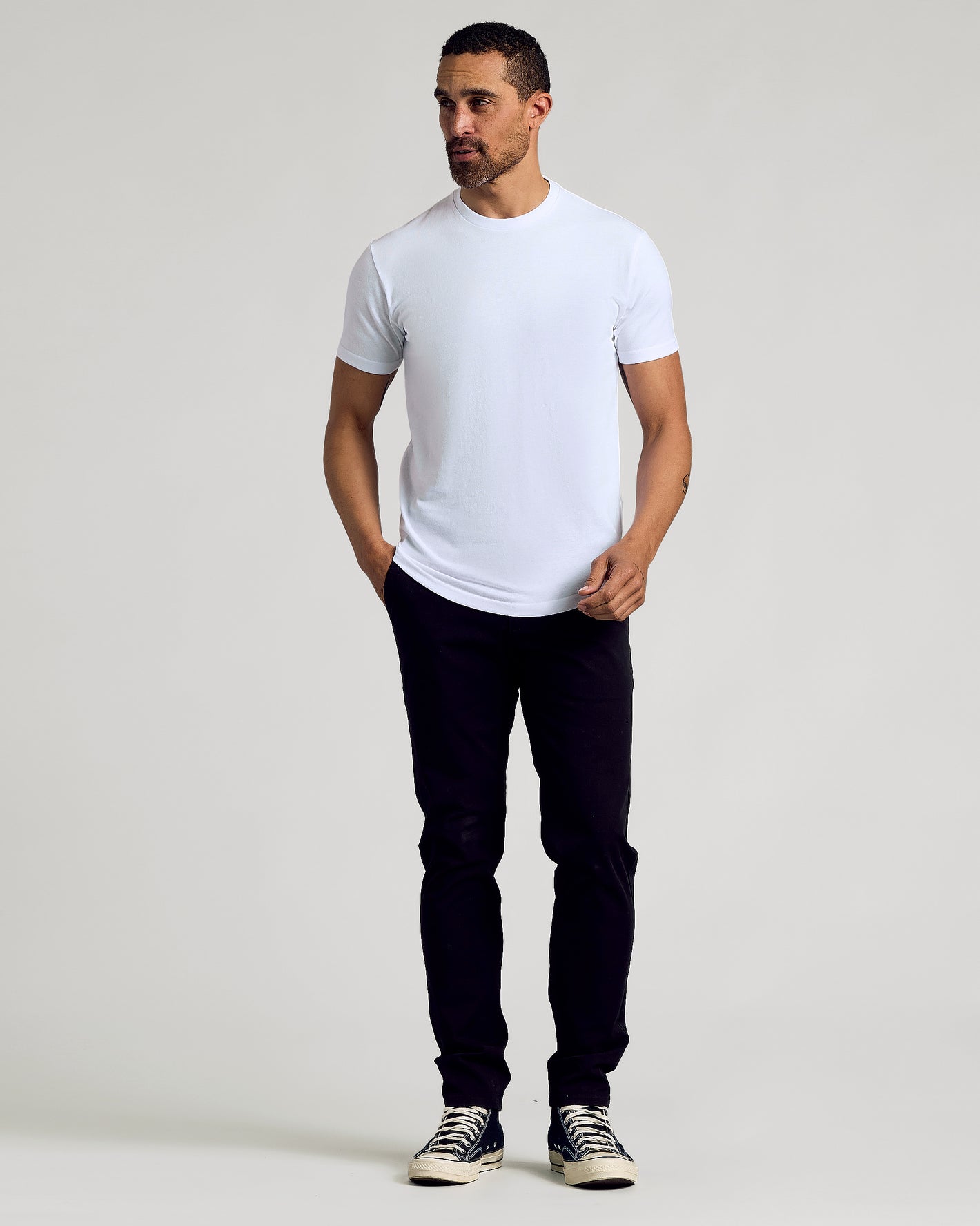 Man wearing Wardrobe Curved Hem Classic Crew Neck T-shirt, slim black pants.