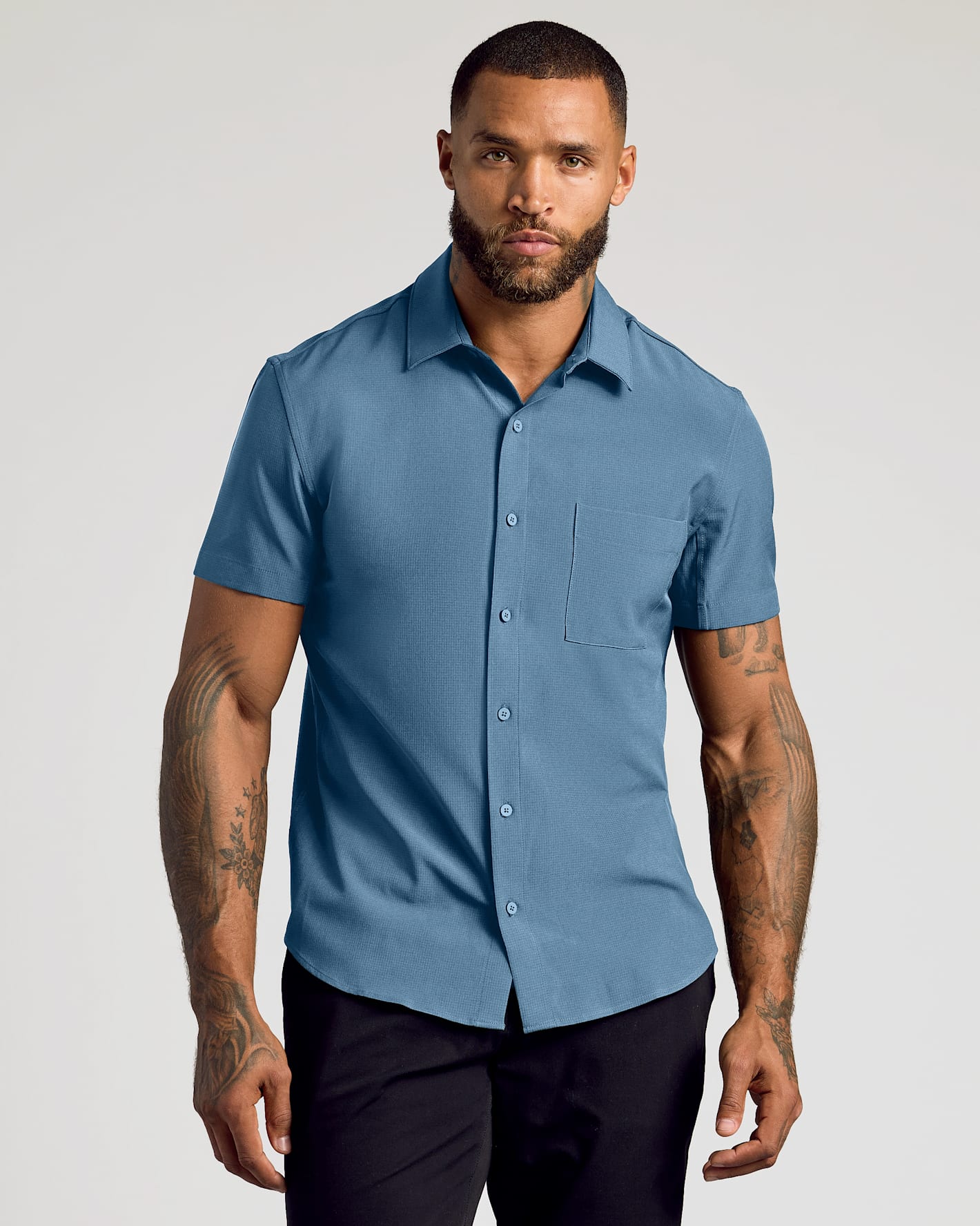 Man wearing Fiord Short Sleeve Ripstop Commuter Shirt, untucked, relaxed pose.