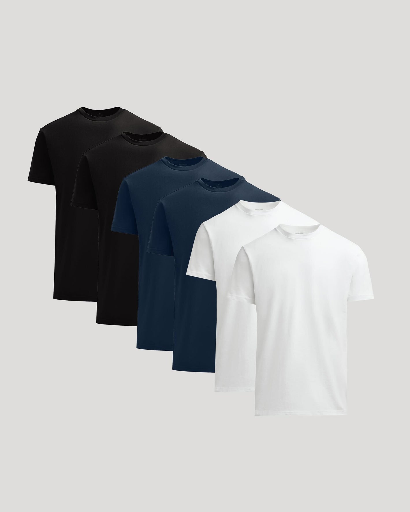 Three black, one navy, and one white t-shirt on a light gray background