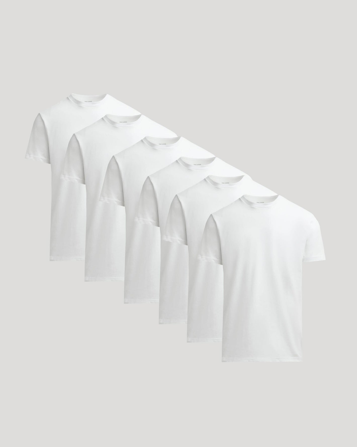 Set of six white t-shirts on a light gray background