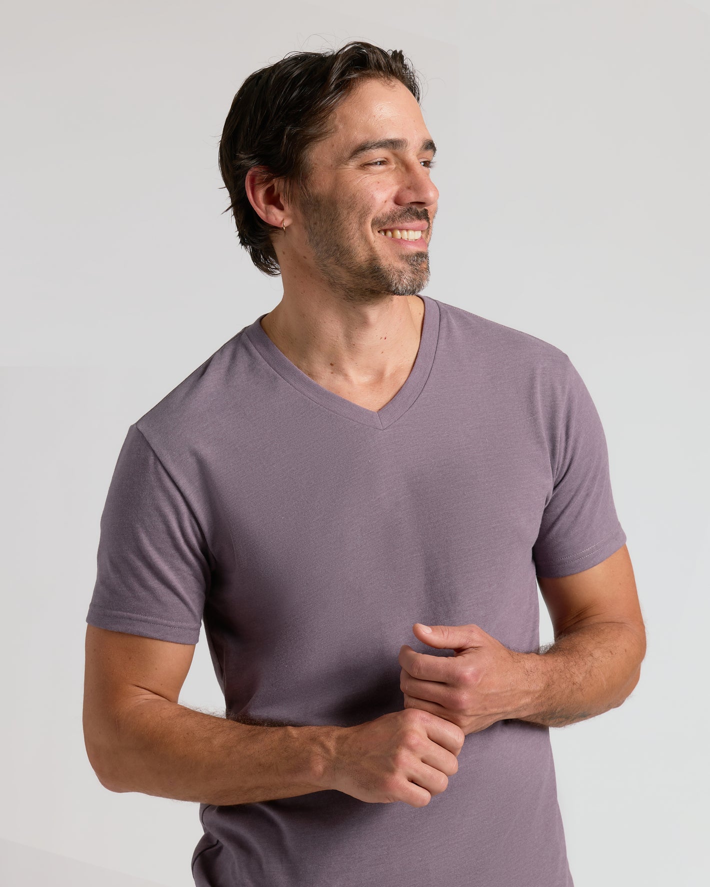 Man in Dark Heather Amethyst Classic V-Neck, smiling, hands clasped.