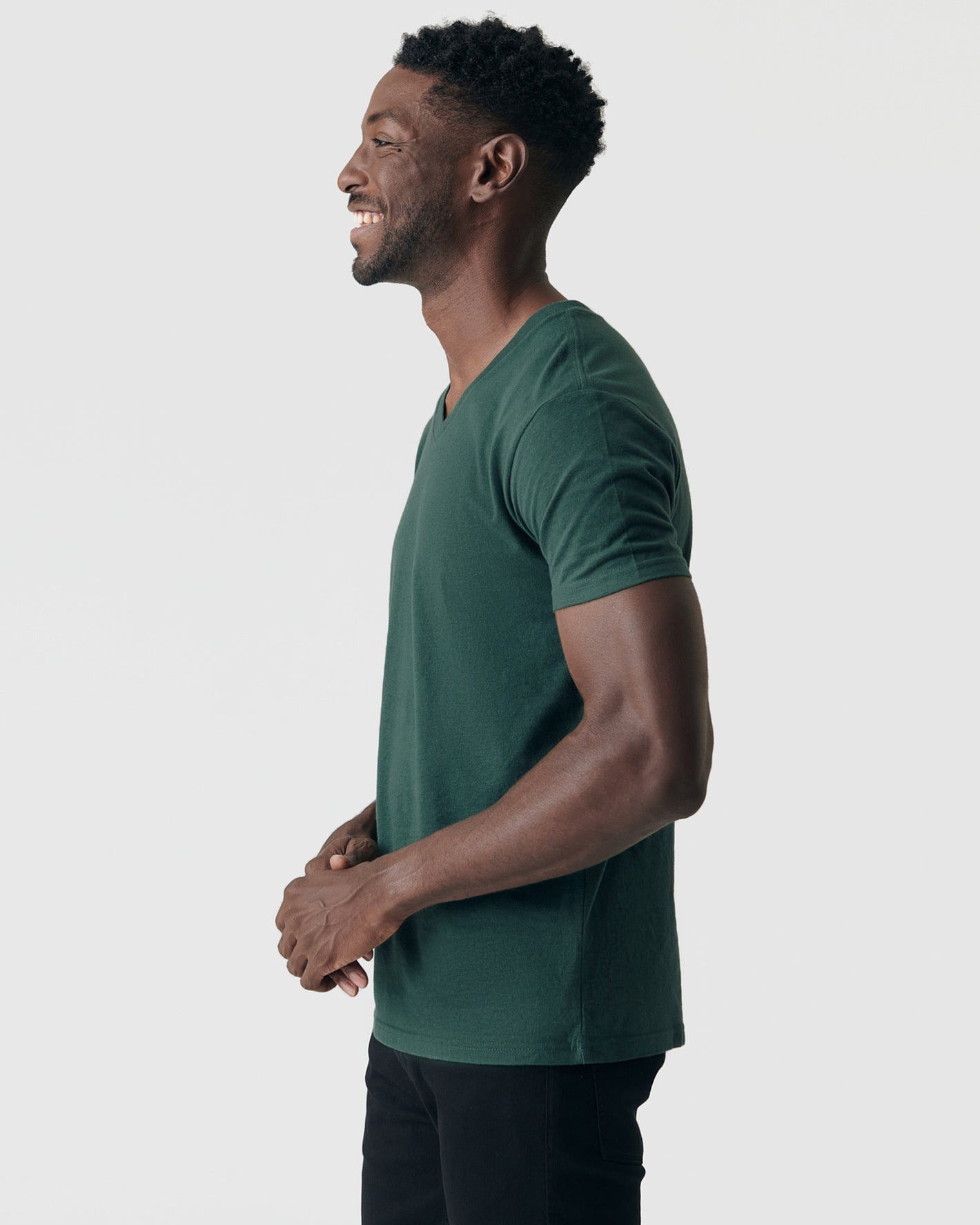 Man wearing Forest Green V-Neck Tee, smiling, in profile view.