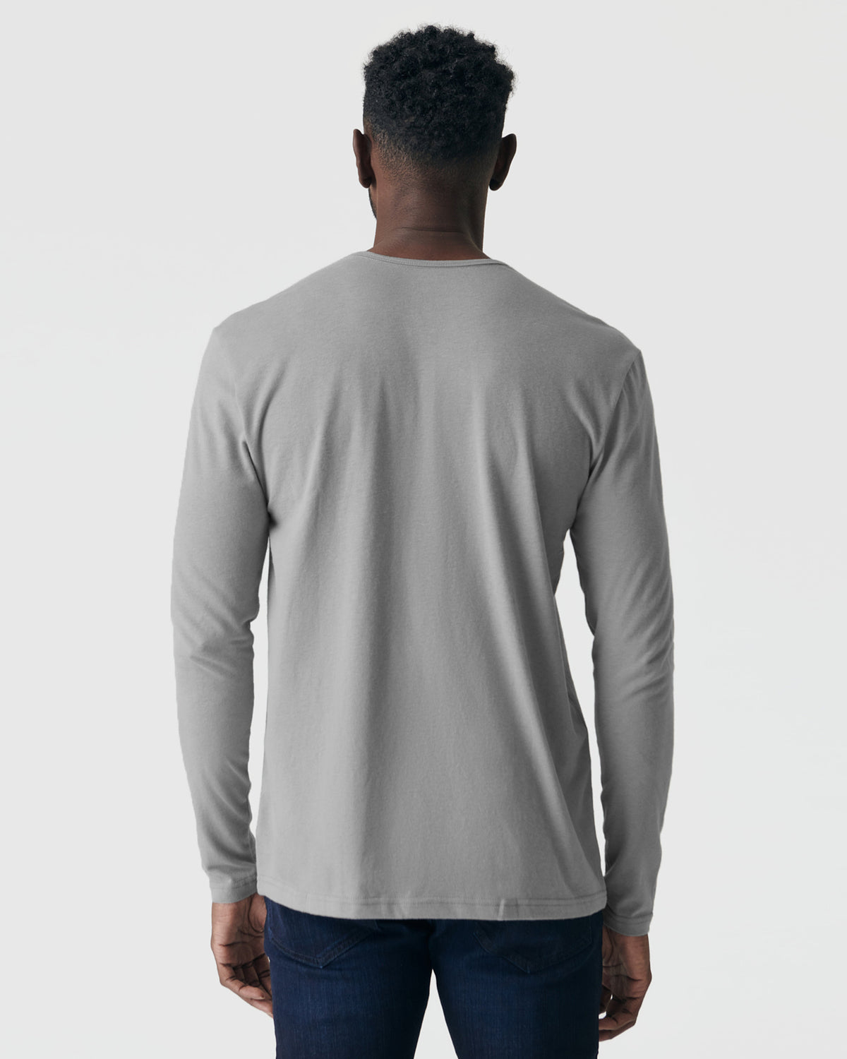 Person wearing Glacier Gray Long Sleeve Henley, paired with dark blue jeans.