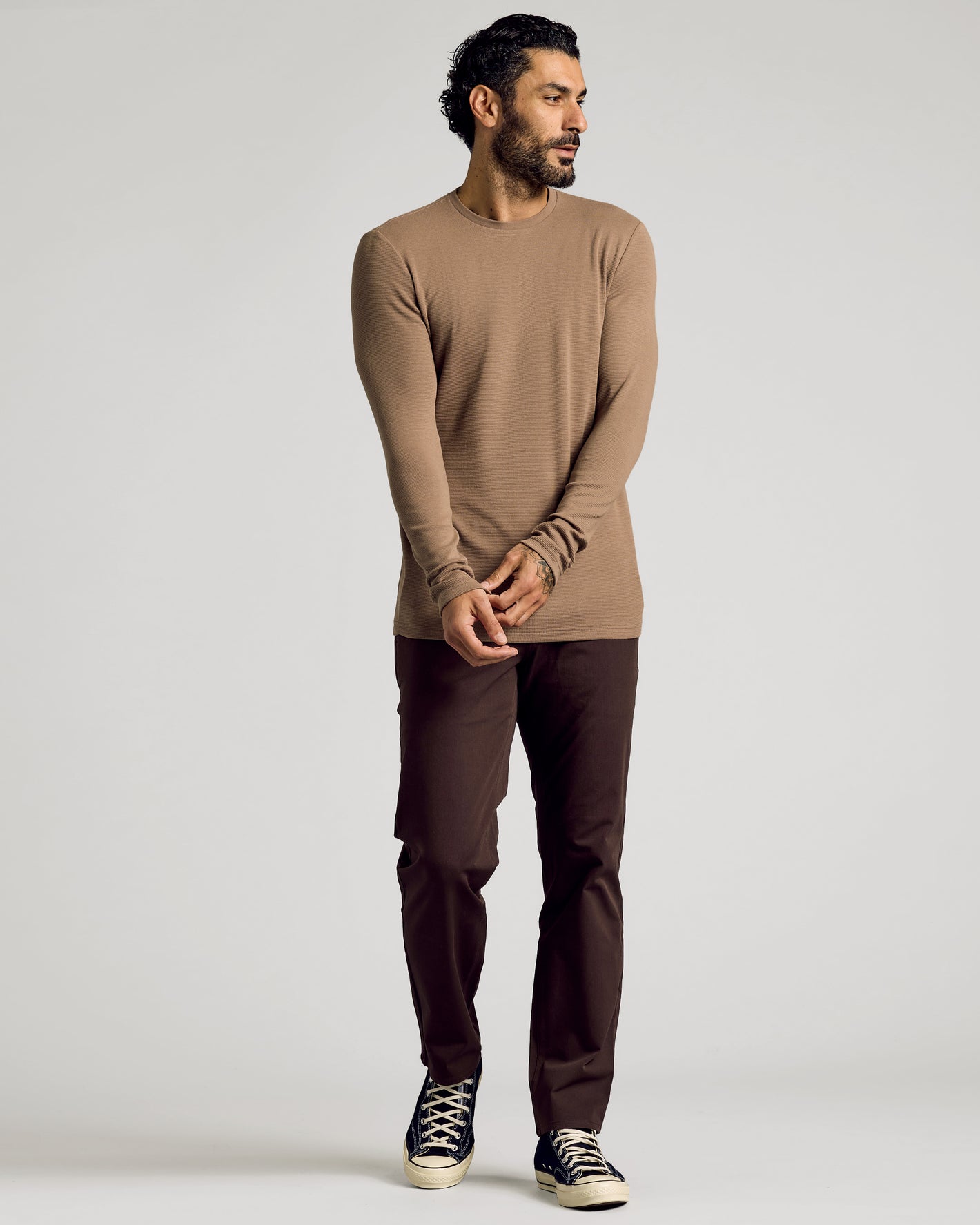 Man wearing Alpaca Waffle Long Sleeve Crew Neck, dark brown pants, navy sneakers.