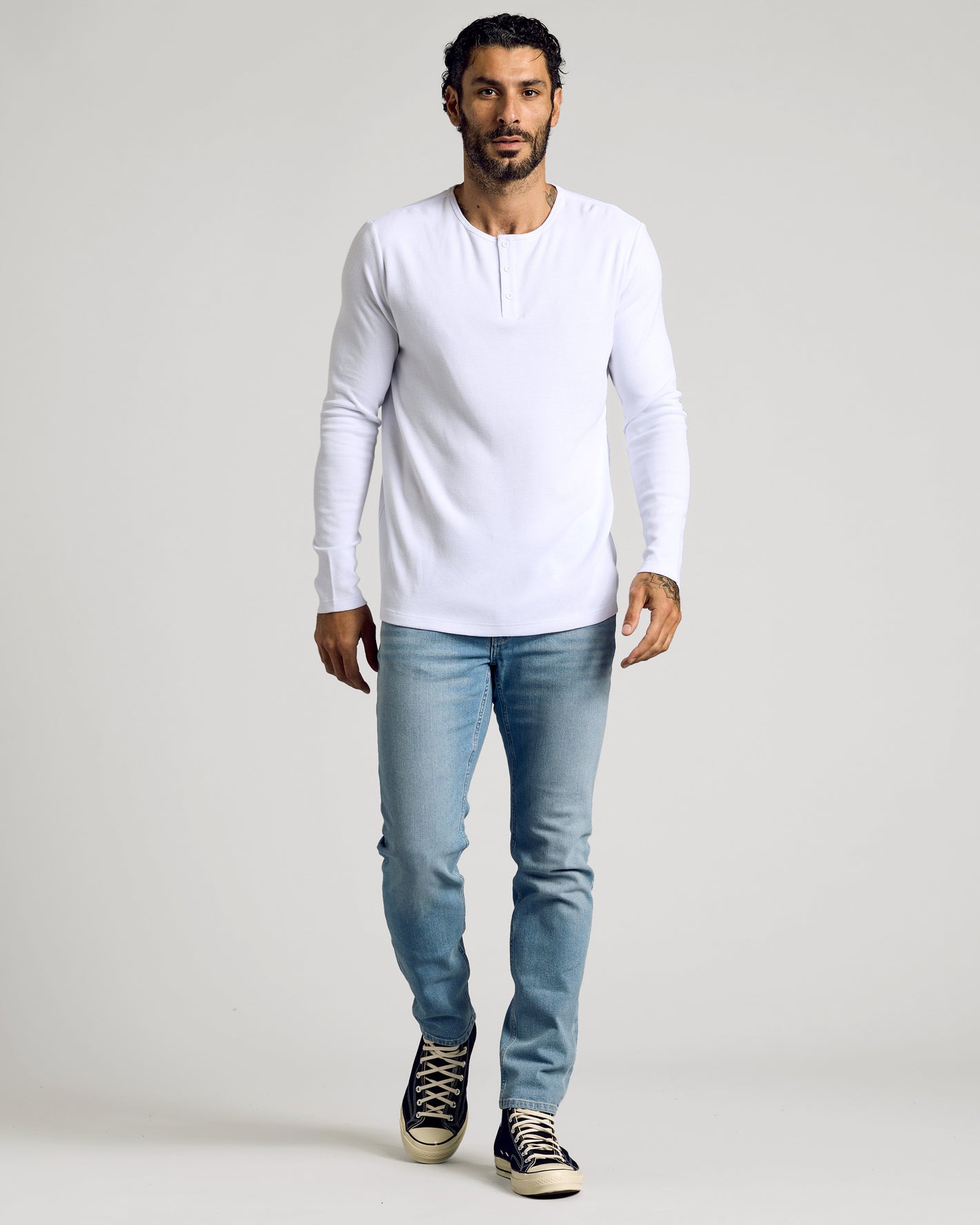 Man wearing a White Waffle Long Sleeve Henley with jeans and sneakers.