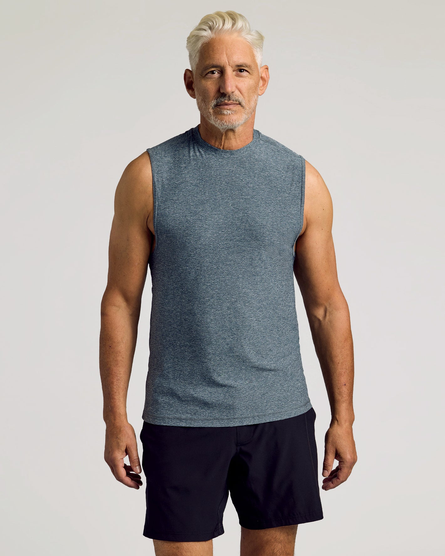 Man wears Heather Navy Sleeveless Active Muscle Tee, showcasing its relaxed fit.