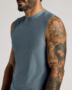 True ClassicClose-up of a man wearing a heather navy sleeveless active muscle tee 3-pack, showcasing his detailed arm tattoo and the muscle fit of the men's basic shirt.