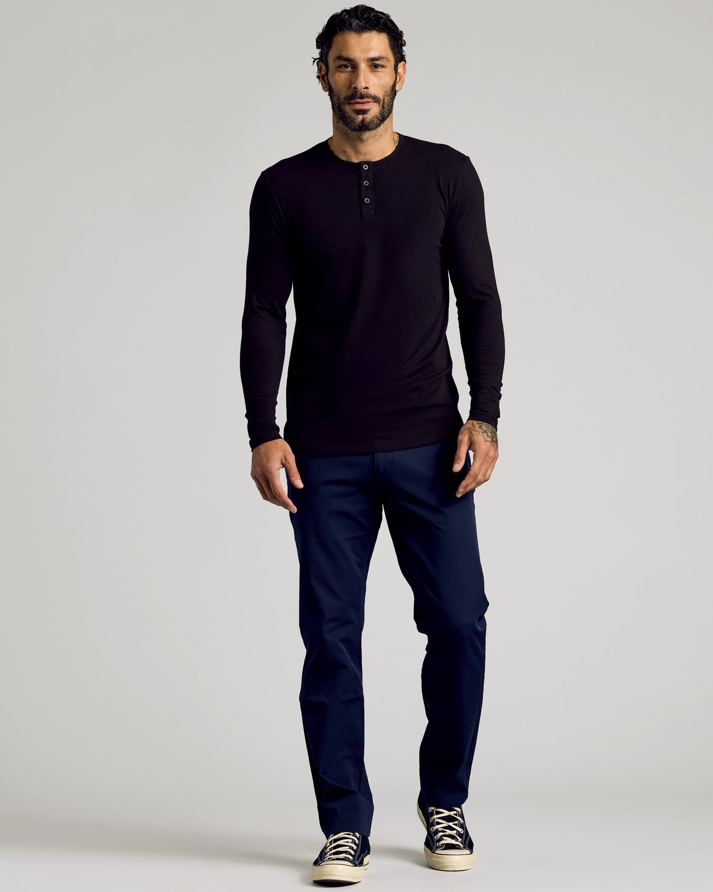 Man wearing All Black Tall Classic Long Sleeve Henley, dark navy pants, sneakers.
