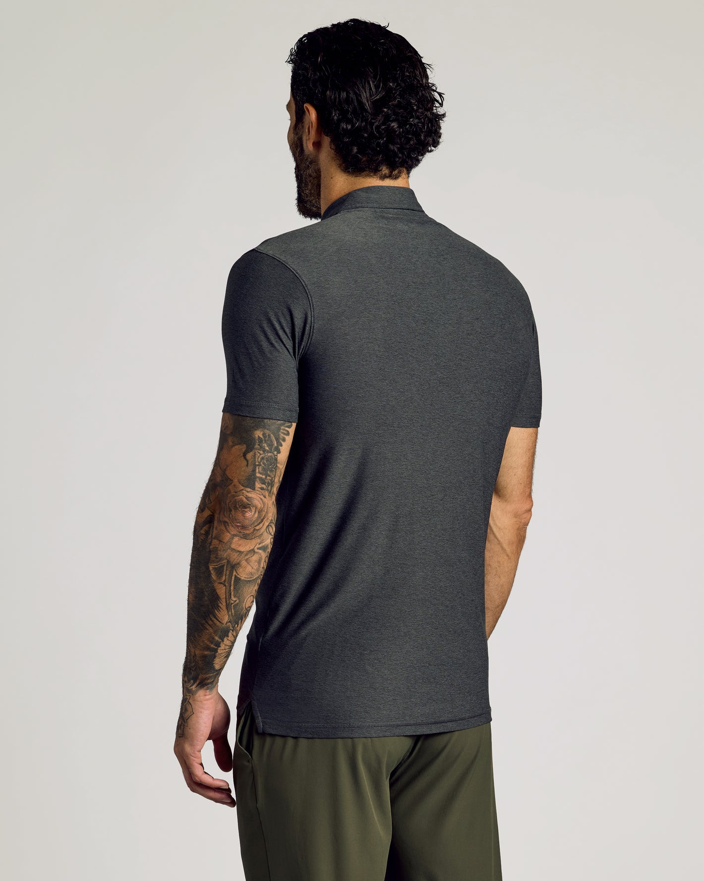 Man in Charcoal Heather Gray Short Sleeve Tall Active Polo, tattooed arm visible.