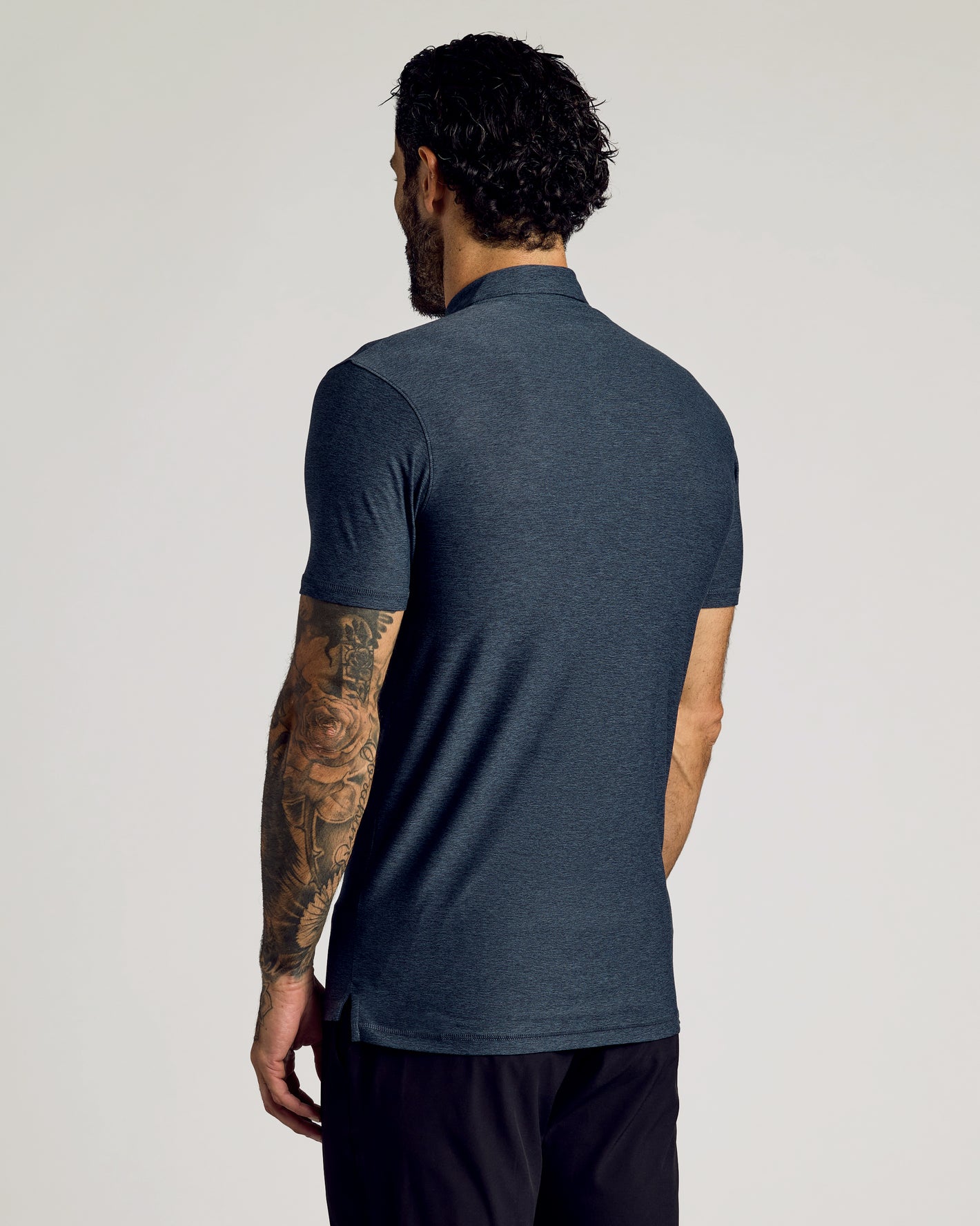 Man wearing Dark Heather Fiord Short Sleeve Tall Active Polo, showcasing tattooed arm.