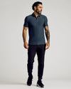 Man wearing Dark Heather Fiord Short Sleeve Tall Active Polo with joggers.