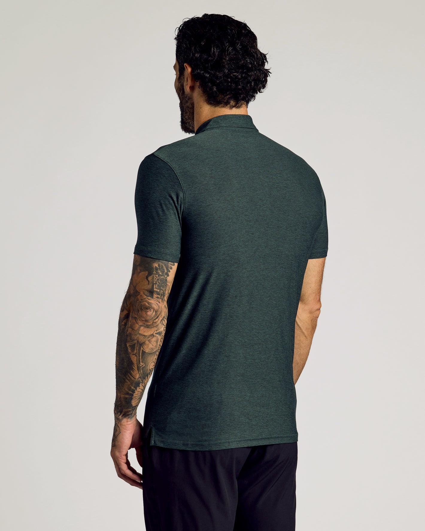 Man in Dark Heather Forest Short Sleeve Tall Active Polo, tattooed arm visible.