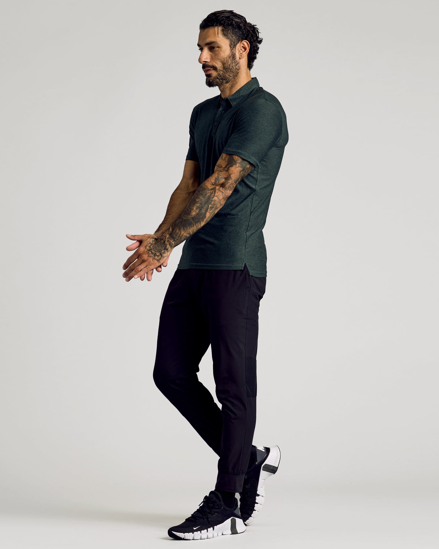 Man in Dark Heather Forest Short Sleeve Tall Active Polo, athletic pose.