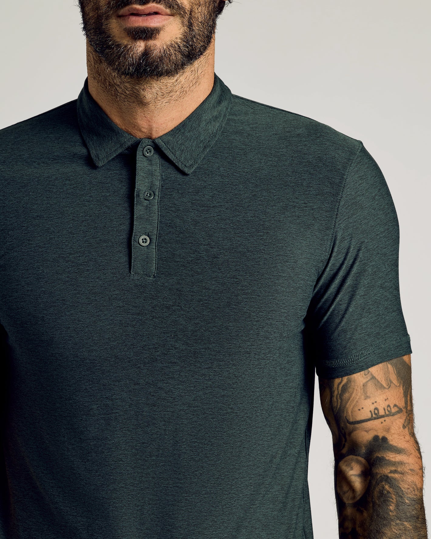 Man wears Dark Heather Forest Short Sleeve Tall Active Polo.