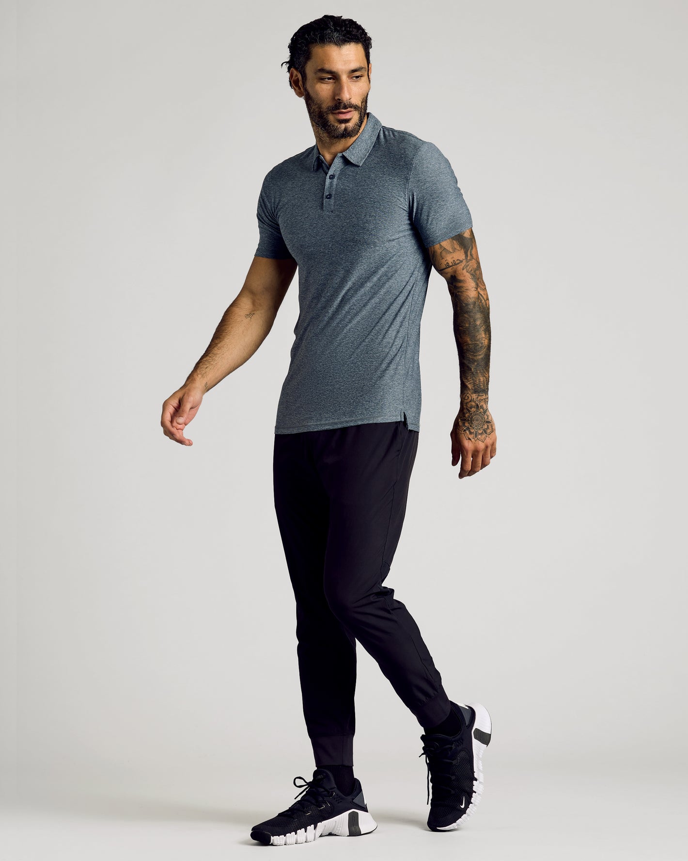 Model in Heather Navy Short Sleeve Tall Active Polo, black joggers, sneakers.