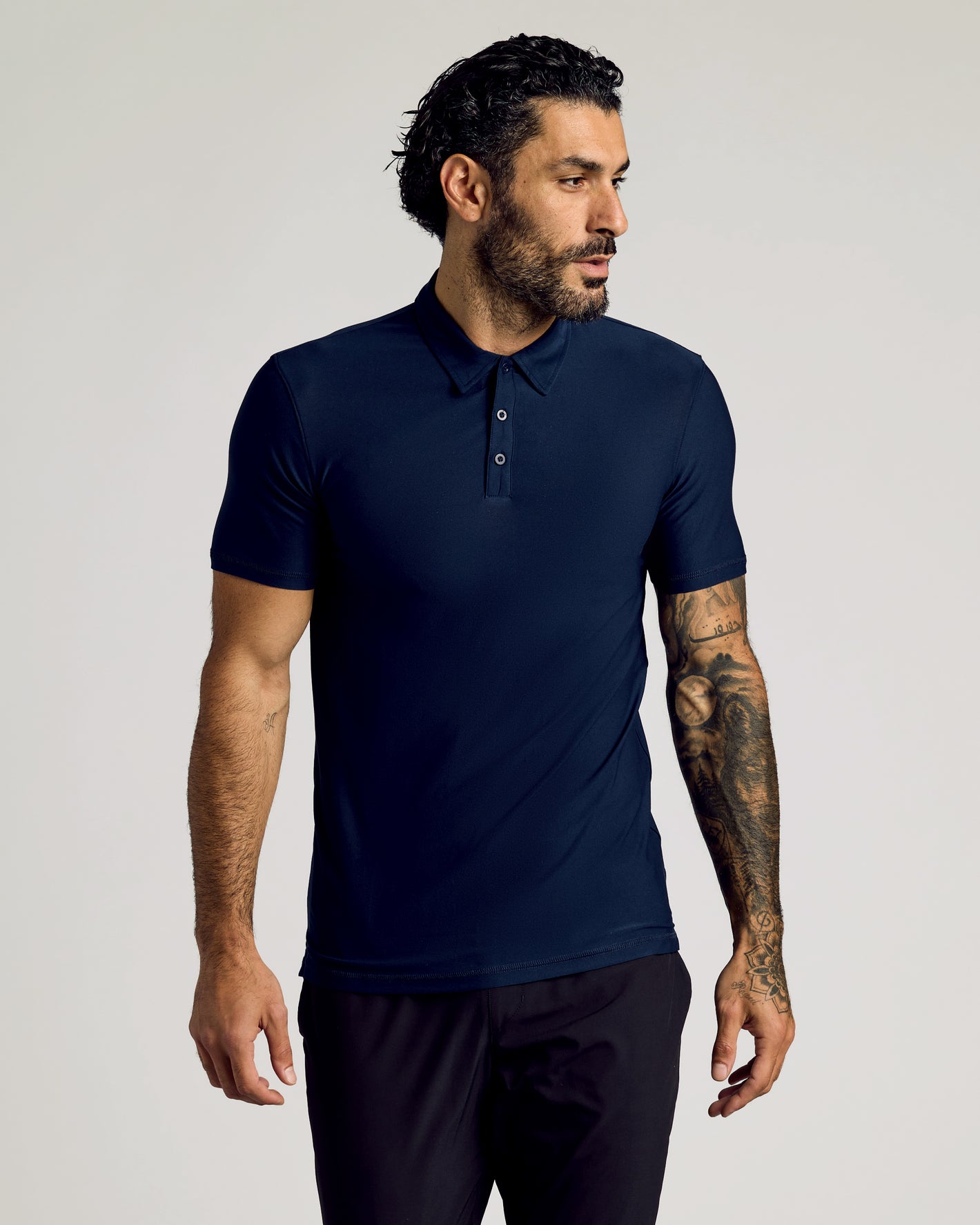 Man in Navy Short Sleeve Tall Active Polo with tattoos.