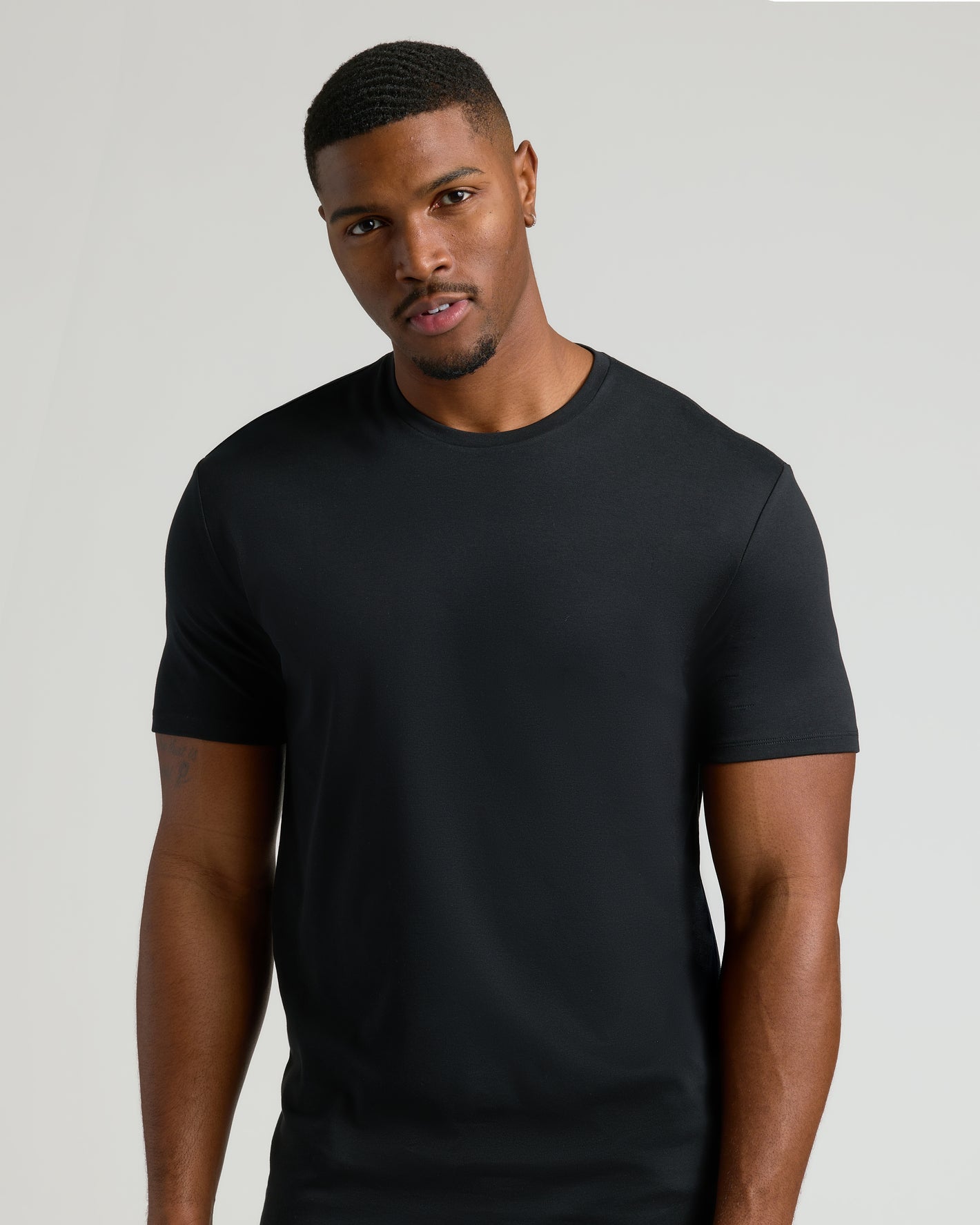 Black Tall Premium Pima Crew Neck 7-Pack on young man, neutral backdrop.